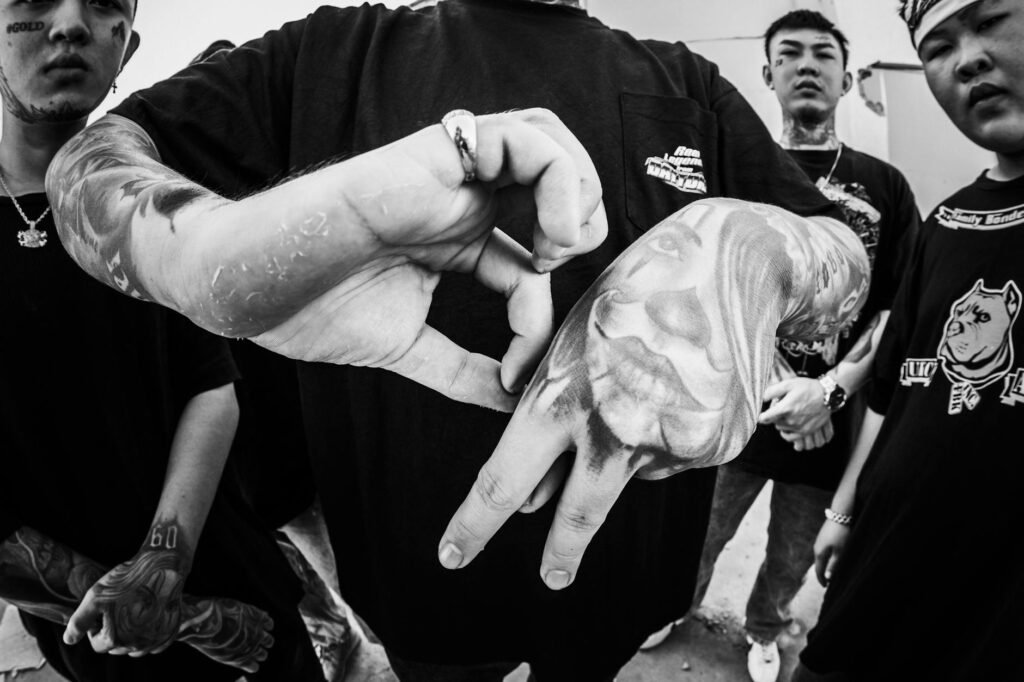 crop cool man showing tattoo between asian friends on street