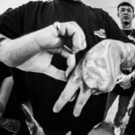 crop cool man showing tattoo between asian friends on street