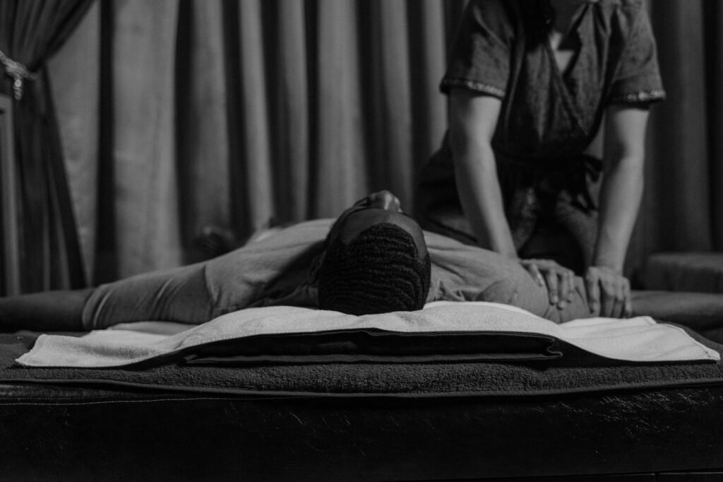 grayscale photo of a woman doing a massage to a man s arm