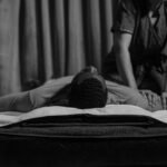 grayscale photo of a woman doing a massage to a man s arm
