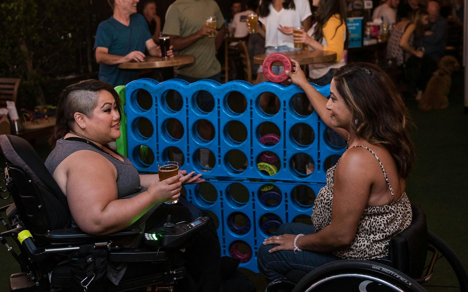 women playing connect four in a bar - fauteuil roulant électrique