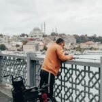 man wearing sweater fishing on riverbank